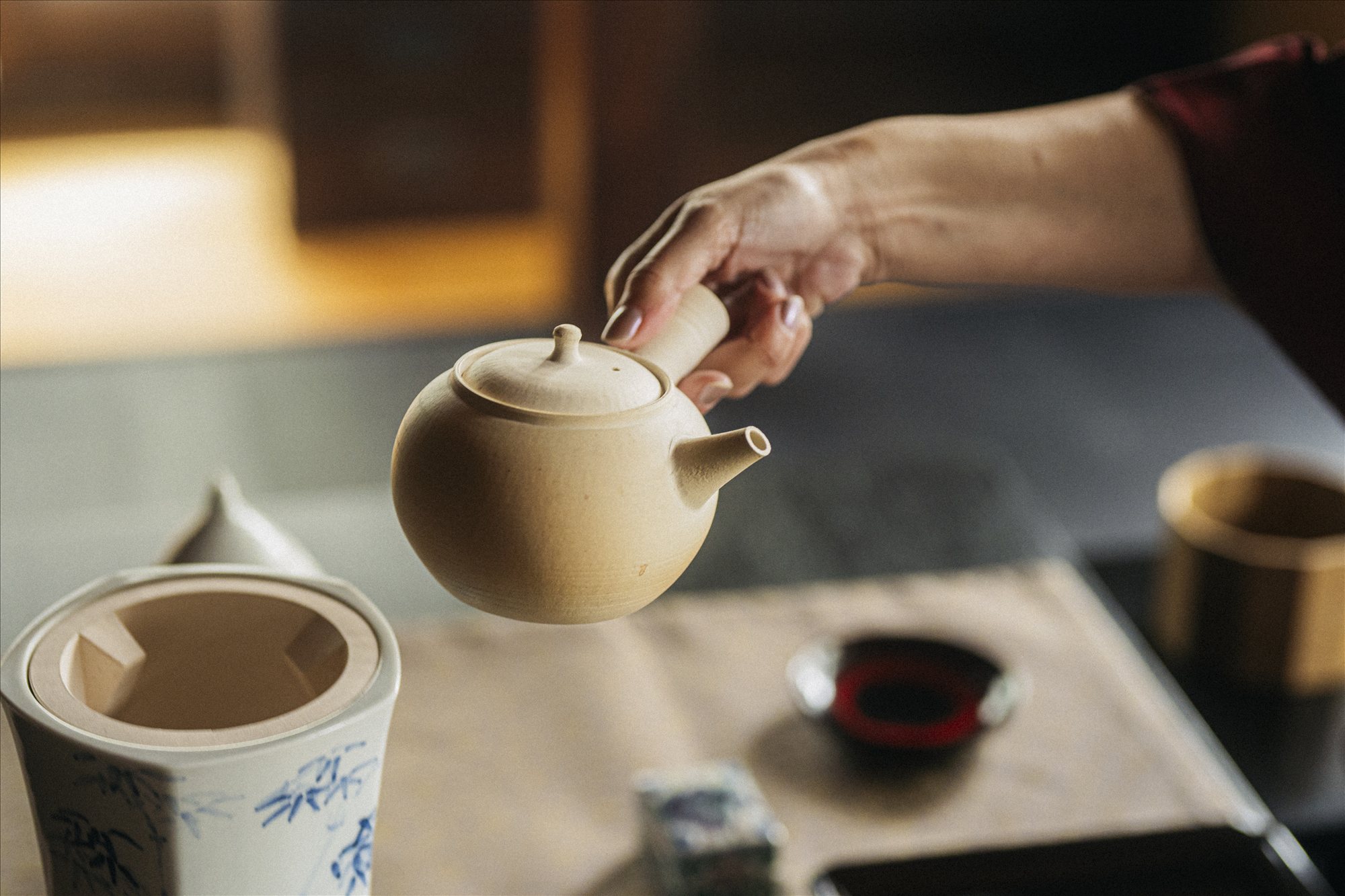 Host holding a kyūsu teapot